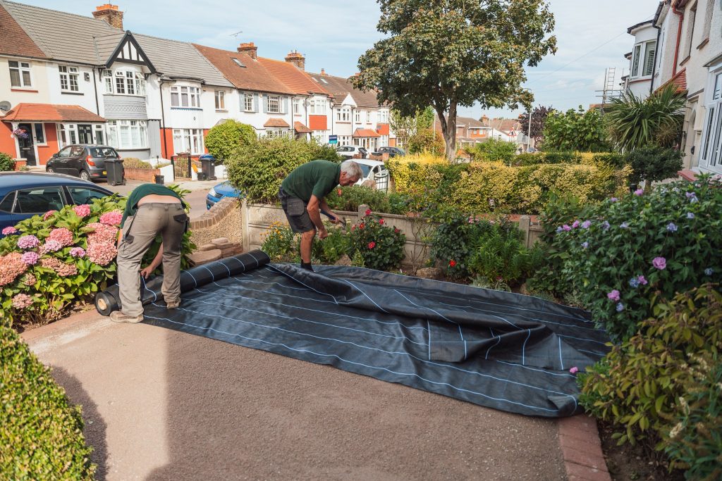 Applying geotextile weed membrane for artifical lawn installation